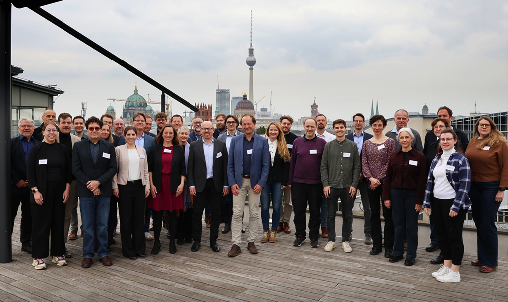 Gruppe von Menschen auf einer Dachterrasse mit Skyline im Hintergrund.